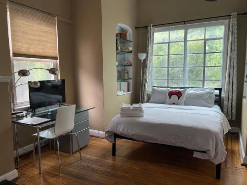 a bedroom with a bed and a desk and a television at The Orange House in Washington, D.C.