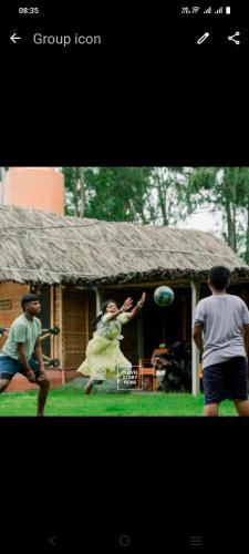 a woman playing with a ball in front of a house at Hampi Waterfall Cottages in Hampi
