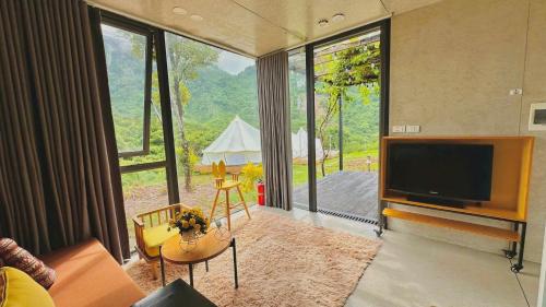 a living room with a tv and a large window at Ora Hill Retreat in Cao Phong