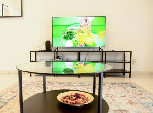 a living room with a tv and a glass table at Modern 4BR Double Storey @ Setia Alam in Shah Alam
