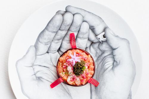 two hands holding a bowl of food on a plate at The Ritz-Carlton Tenerife, Abama in Guía de Isora