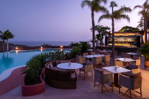 a restaurant with tables and chairs next to a pool at The Ritz-Carlton Tenerife, Abama in Guía de Isora
