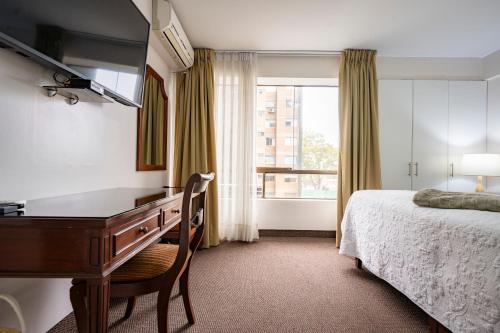 a bedroom with a desk and a bed and a window at Apart Hotel San Martin in Lima