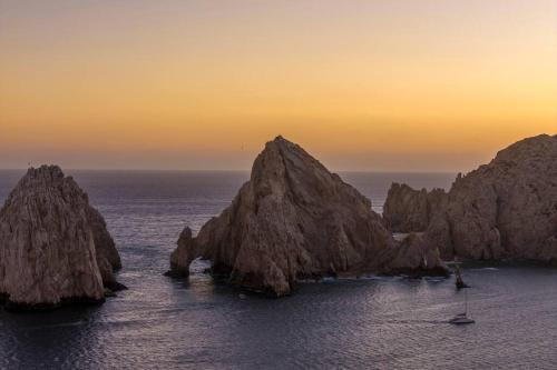 a group of rocks in the ocean at sunset at New 3BR in the Heart of San Lucas in Cabo San Lucas