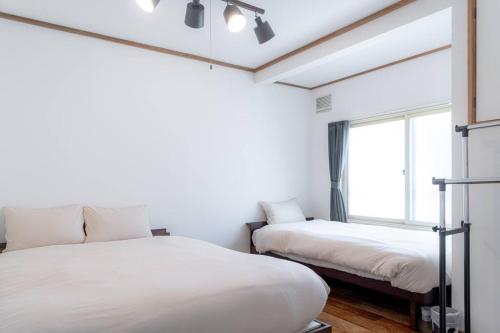 a bedroom with two beds and a window at KAKUREGA by unito in Hakodate