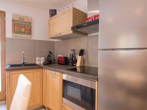 une cuisine avec un réfrigérateur en acier inoxydable et des armoires en bois dans l'établissement 2 pièces 6 pers, terrasse, parking, animaux acceptés - FR-1-263-539, à Valloire