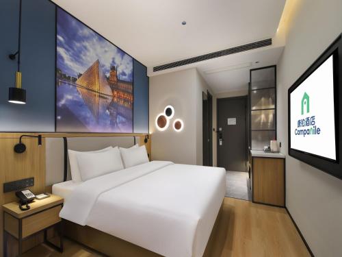 a bedroom with a white bed and a flat screen tv at Campanile Shanghai Oriental Beauty Valley Avenue Xianpu Road in Fengxian
