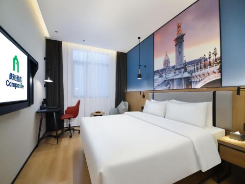 a hotel room with a white bed and a tv at Campanile Shanghai Oriental Beauty Valley Avenue Xianpu Road in Fengxian