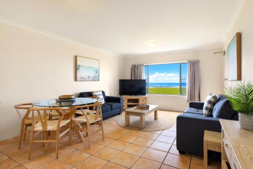 a living room with a blue couch and a table at Absolute Beachfront Apartment 2B in Lennox Head