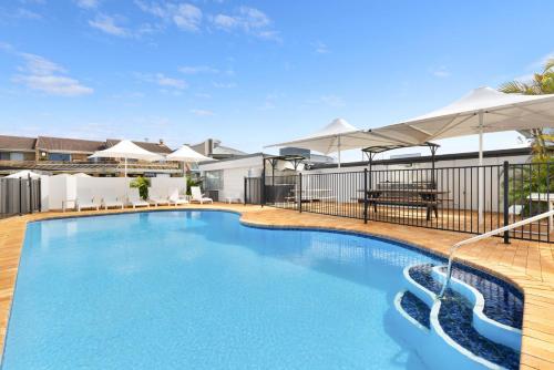 a swimming pool with blue water and white umbrellas at Apartment 7T in Lennox Head