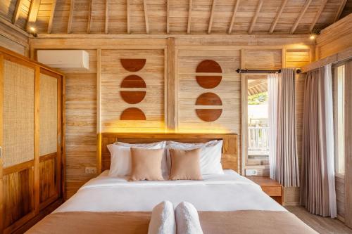 a bedroom with a bed with wooden walls at Cove D Ancak Villa and Bungalow in Nusa Dua