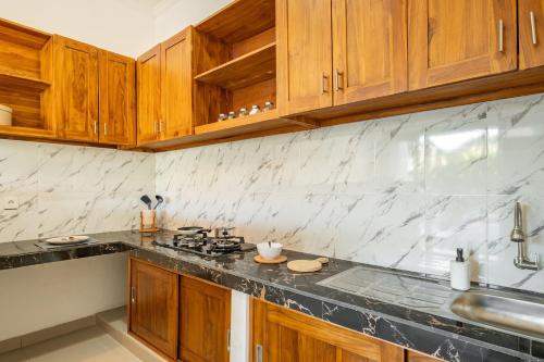 a kitchen with wooden cabinets and a counter top at Cove D Ancak Villa and Bungalow in Nusa Dua
