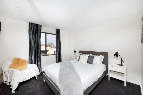 Un dormitorio blanco con dos camas y una ventana. en Griffin Apartments Kingston ACT, en Canberra
