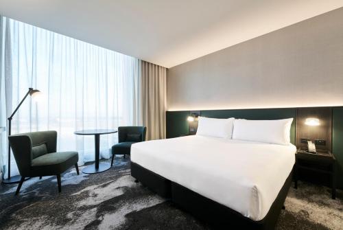 a hotel room with a bed and a table and chairs at Novotel Melbourne Airport in Melbourne
