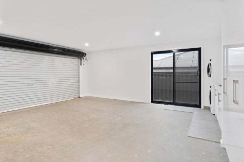 an empty garage with a garage door and a large door at Sleek & Stylish Family Retreat in Shorewell Park in Cooee