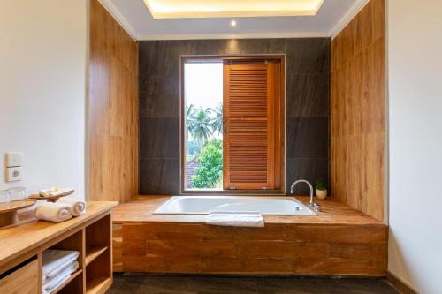 a bathroom with a large tub with a window at Bije Boutique & Gallery in Ubud