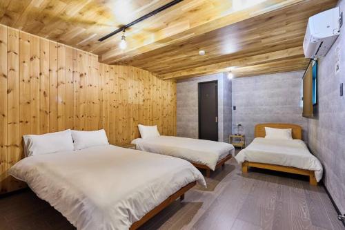 two beds in a room with wooden walls at The No 10 Fuji Yamanakako in Yamanakako