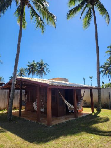 ein Haus mit Hängematte und Palmen in der Unterkunft Vila do Rico in São Gonçalo do Amarante