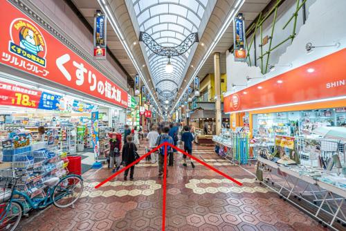 a group of people walking through a shopping mall at Tomo house in Tokyo