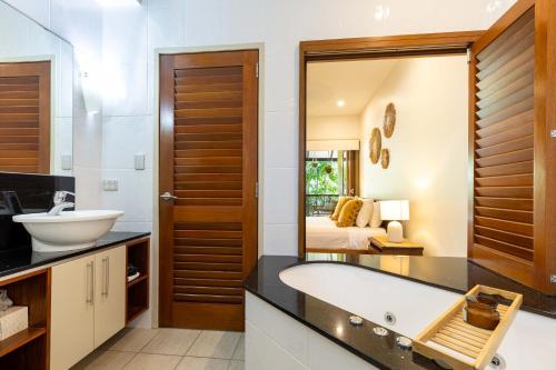 a bathroom with a tub and a sink and a bedroom at The Savannah Villa in Port Douglas