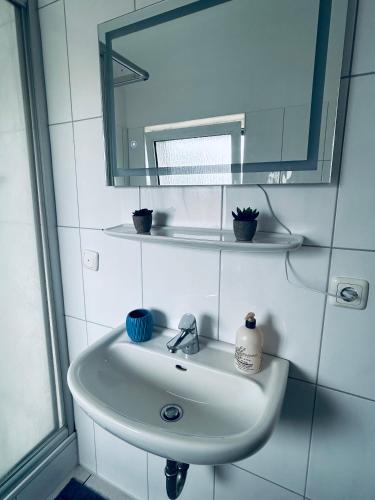 a white sink in a bathroom with a mirror at Perle Doppelzimmer mit separatem Bad in Hüde