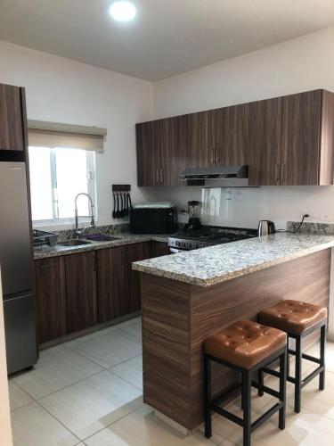a kitchen with wooden cabinets and a counter with stools at Casa Punta Arena in Los Bledales
