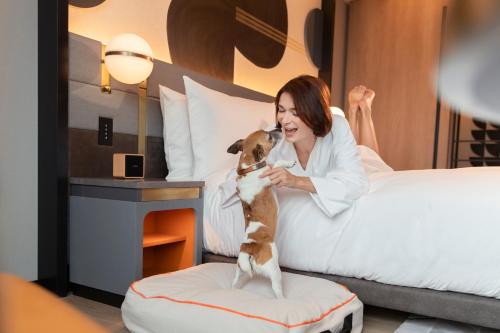 a woman sitting in a bed with a dog at Canopy By Hilton Osaka Umeda in Osaka
