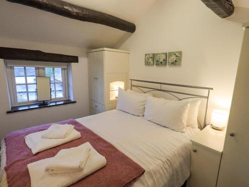 a bedroom with a bed with two towels on it at Cobblestone Cottage in Ambleside