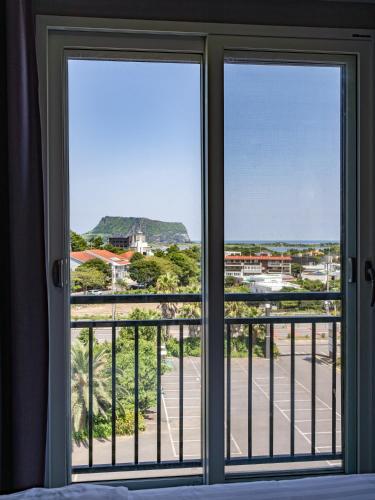a bedroom with a window looking out at the ocean at Cordelia Hotel in Seogwipo