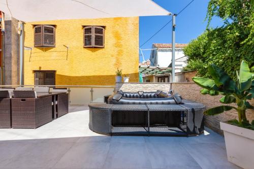 a patio with a table and chairs and a yellow building at Villa bella in Mali Lošinj