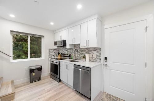 a kitchen with white cabinets and a stove top oven at Entire new small home in Vancouver