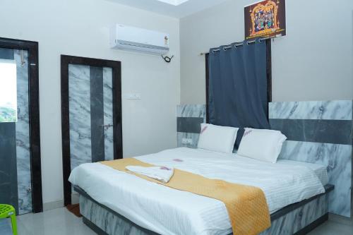 a bedroom with a large bed with a blue curtain at Vashistha Residency in Bhadrāchalam