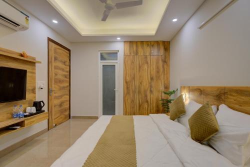 a bedroom with a large white bed and a television at The Lodgers Luxury 1 BHK Serviced Apartment in Gurugram Near Millennium City Centre Metro in Gurgaon