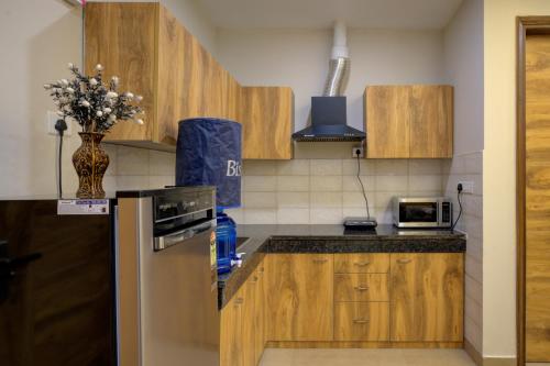 a kitchen with wooden cabinets and a vase of flowers on the counter at The Lodgers Luxury 1 BHK Serviced Apartment in Gurugram Near Millennium City Centre Metro in Gurgaon