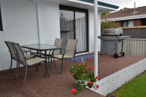 a patio with a grill and a table and chairs at Dolphin Lodge Albany - Self Contained Apartments at Middleton Beach in Albany