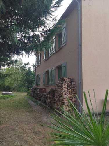 un bâtiment avec des fenêtres vertes et une pile de briques dans l'établissement Chez Yves , 200 m du canal , 7 min de Golfech , parking privé et gratuit , rangement vélo fermés, à Pommevic