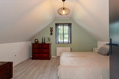 a attic bedroom with a bed and a window at Casa Black Nature in Holten