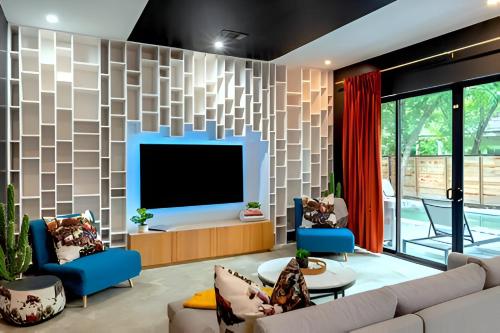 a living room with a television and blue chairs at Backyard Pool Oasis - Rainey Street - 6 min walk in Austin