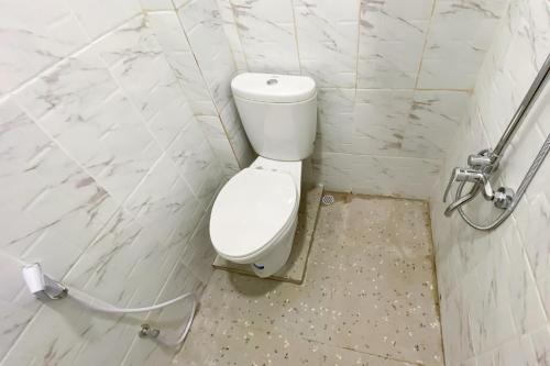 a white toilet in a bathroom with marble walls at RedDoorz Syariah near RS Awal Bros Panam Pekanbaru in Kubang