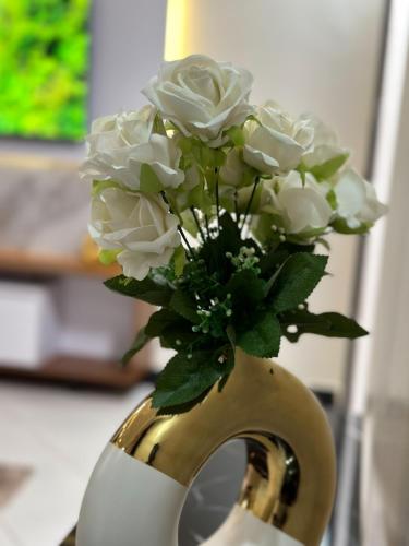 a yellow and white vase with white roses in it at Livluxe Apartments 7 in Kampala