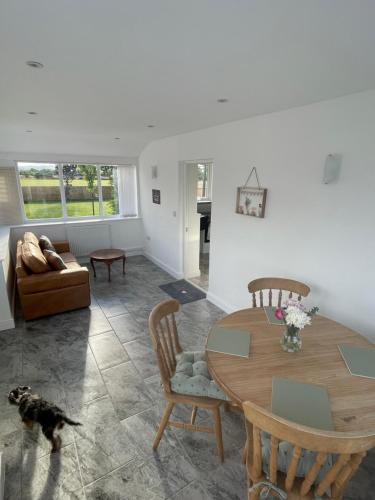 a living room with a dining room table and a dog at Wisteria Barn hot tub holidays in the Cotswolds in Badsey