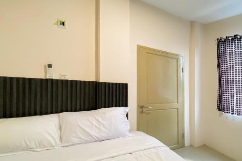 a bedroom with a bed with white sheets and a door at RedDoorz Syariah near RS Awal Bros Panam Pekanbaru in Kubang