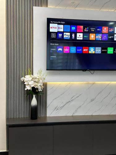 a vase of flowers on a table with a television at Livluxe Apartments 6 in Kampala