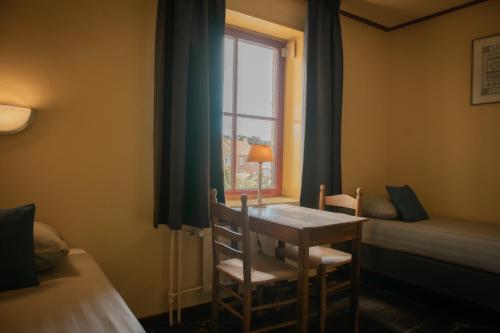 a room with a table and two beds and a window at Hotel Groede in Groede