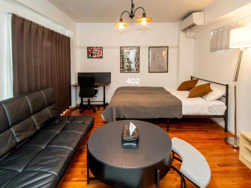 a bedroom with a bed and a couch and a table at Matsufuji 4F 401 or 402 in Naha
