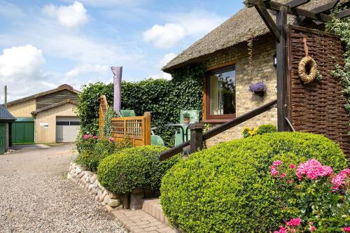 a house with bushes and flowers in front of it at Ferienwohnung am Eiderdeich in Delve