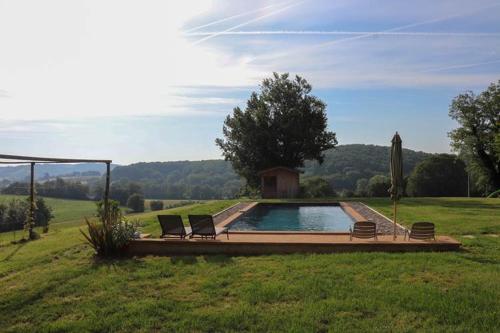 - une piscine dans un champ avec 2 chaises dans l'établissement chambres d hôtes Puchouaou Chêne sur le chemin de Saint Jacques de compostelle, à Montesquiou