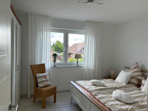 ein weißes Schlafzimmer mit einem Bett und einem Fenster in der Unterkunft Ferienwohnung Harms, 85116 in Ostrhauderfehn