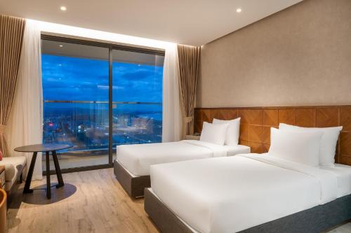 una camera d'albergo con due letti e un tavolo di HaNaLi - Apec Mandala Wyndham Phú Yên Condotel a Tuy Hoa