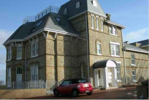 a red car parked in front of a large brick building at Isle of Wight Seaview in Shanklin